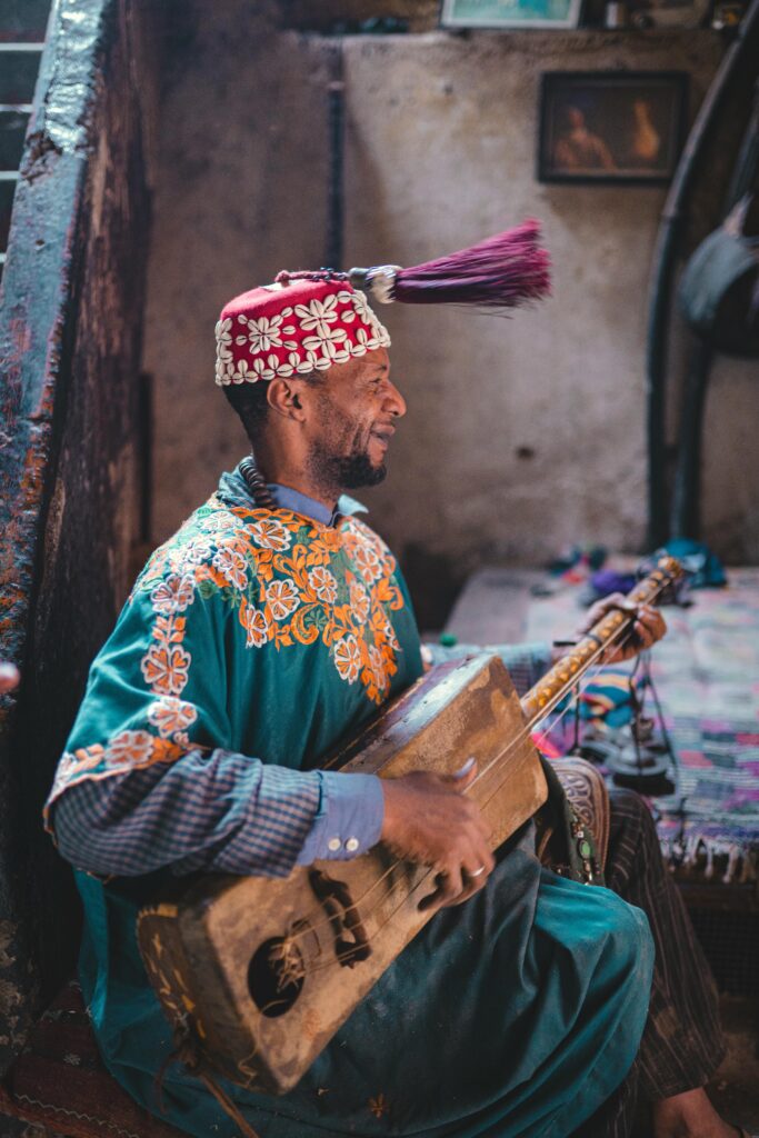 Musician in Marrakesh playing the guembri, showcasing vibrant traditional attire.
